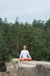 person meditating on a cliff