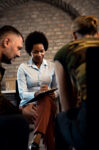 Female psychologist talking to group of diverse veterans during PTSD support group.