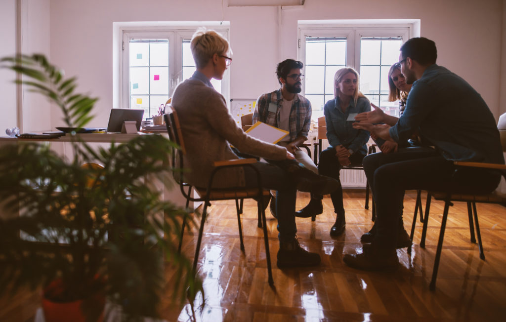 Young people with problems having a discussion while sitting together on special group therapy.