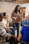 Woman Standing To Address Self Help Therapy Group Meeting In Community Center