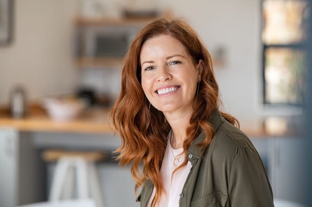 Portrait of smiling mature woman looking at camera with big grin.