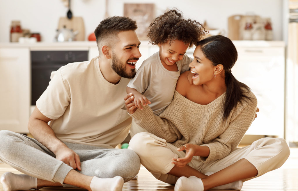 happy family multiethnic mother, father and son  laughing, playing,and tickles  on floor in cozy kitchen at home