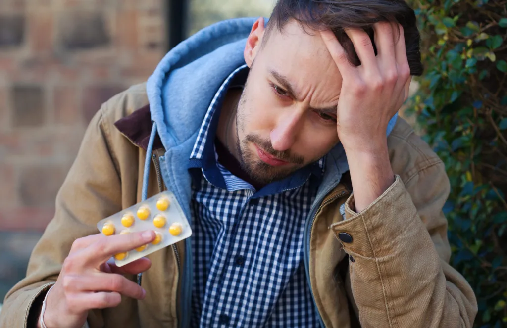 Young man taking medicines and experiencing side effects