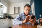 Mature man using mobile phone at home