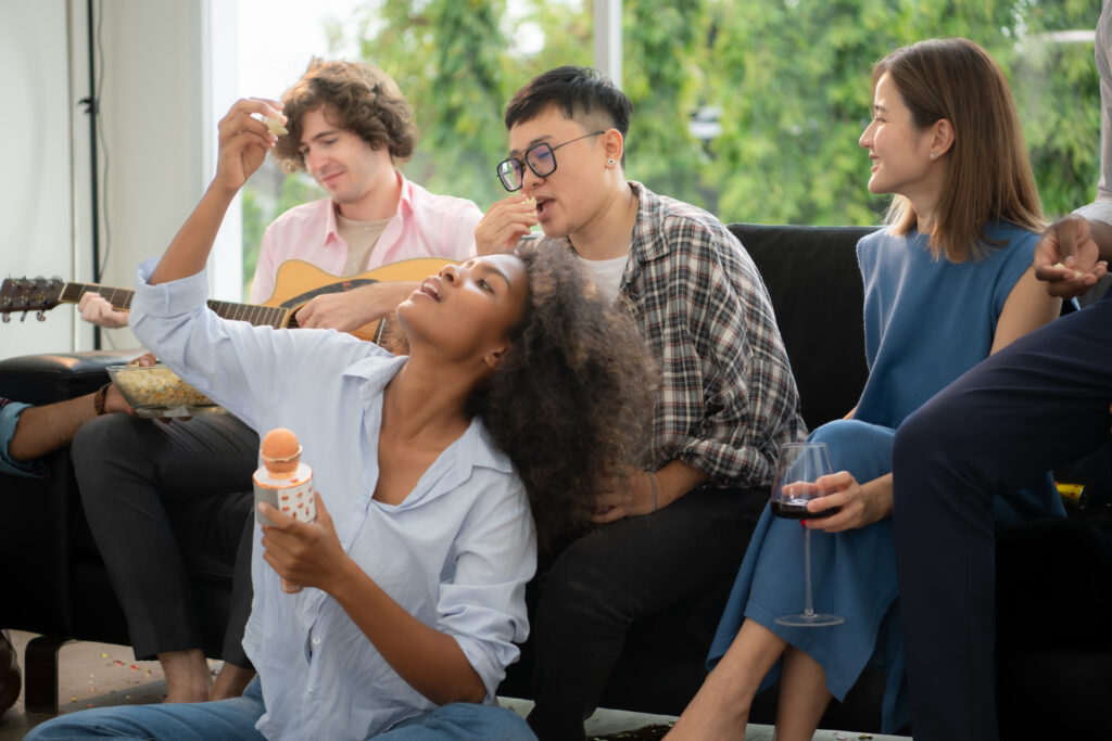 Group of multiethnic friends having fun at party by playing guitar and singing together at home.